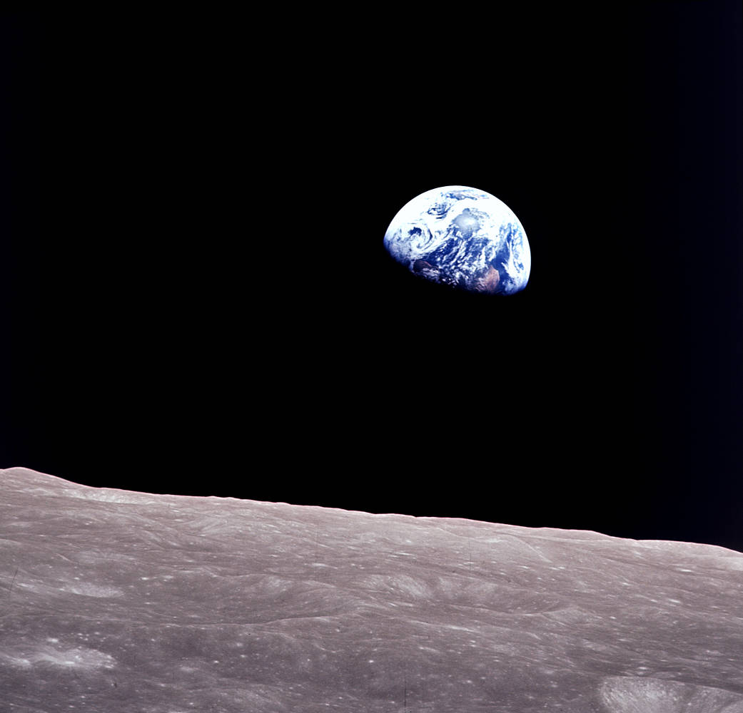 Earthrise, photographed by the Apollo 8 crew on 24 December 1968: the half-lit Earth over the grey horizon of the Moon
